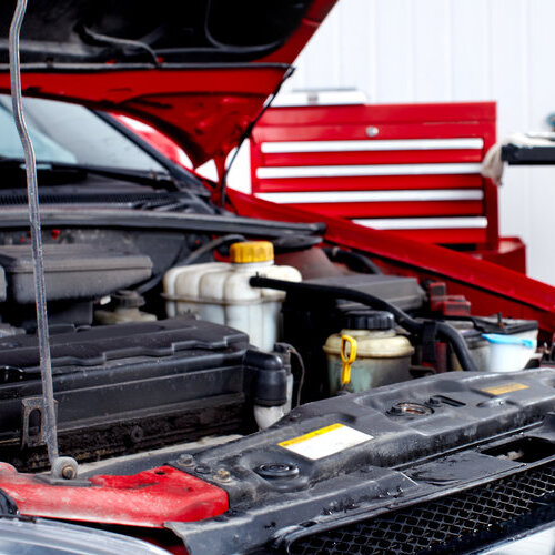 open hood showing the engine of a red sedan